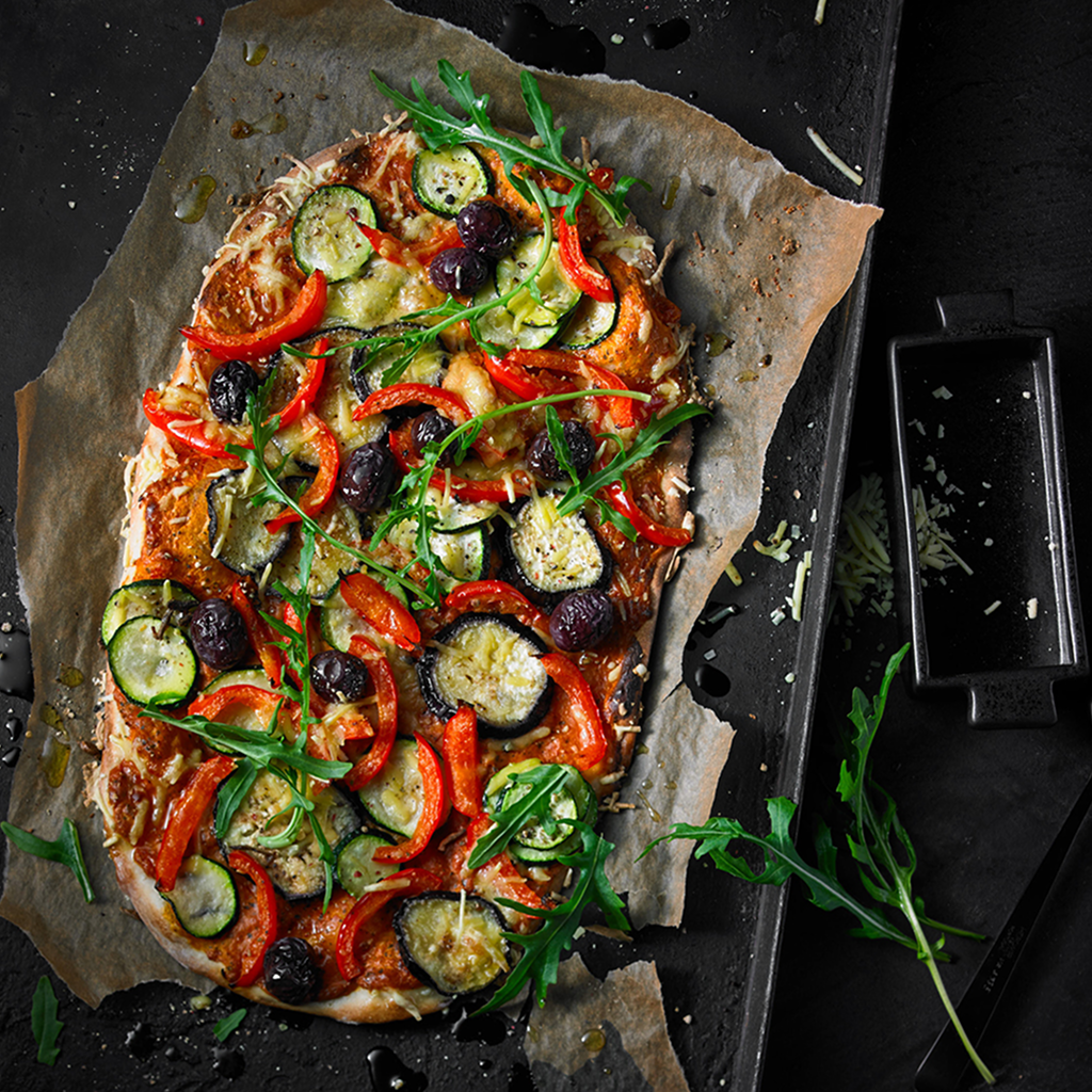 Frisch gebackener Flammkuchen Style Antipasti Vegan mit knusprigem Boden, mediterranen Antipasti, frischen Toppings und aromatischer veganer Sauce auf einem Brett serviert.